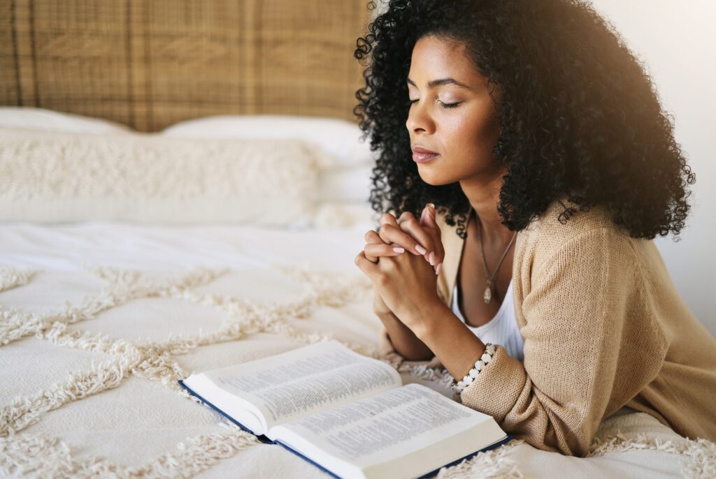 Bible, prayer and black woman praying on bed in bedroom home for hope, help or spiritual faith. God