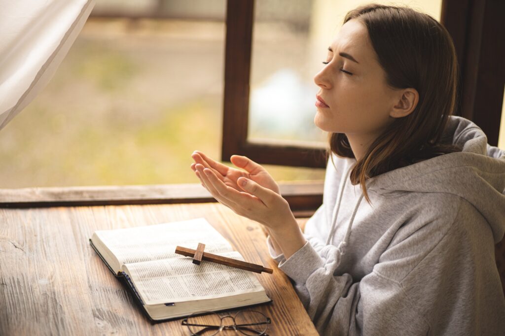 The girl reading the Bible and prays. Prayer. Faith and religion. Believing girl praying. Bible.